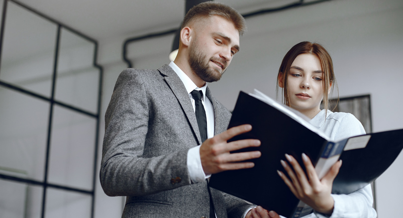 hombre y mujer consultando un libro de leyes