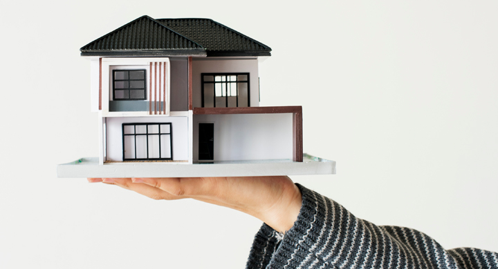 imagen de una mano sujetando la maqueta de una casa